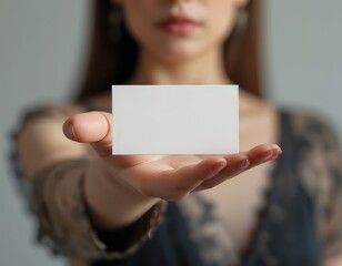 Los delgados dedos de una mujer refinada acunan una tarjeta de visita blanca