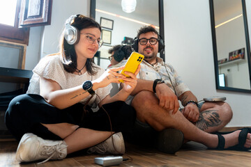 Millennials listening music with headphones and choosing songs on smartphone