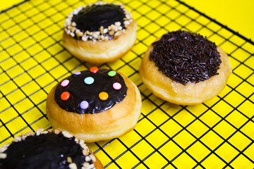 closeup row of sweet donuts with various flavors neatly arranged isolated on yellow background