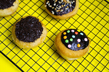 closeup row of sweet donuts with various flavors neatly arranged isolated on yellow background