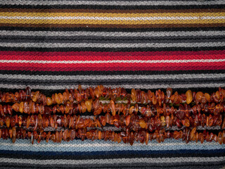 Amber beads lined horizontally on colorful striped wool fabric