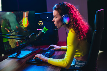 Charming girl gamer streaming live video game in vibrant neon lighting at home during an evening...
