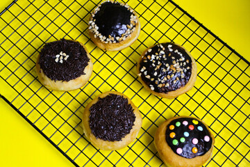 closeup row of sweet donuts with various flavors neatly arranged isolated on yellow background