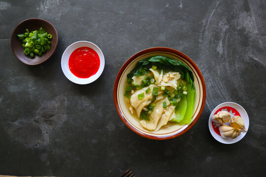wonton soup or pangsit or dumplings soup and vegetable. wonton is traditional Chinese food of minced meat wrapped in flour sheets