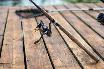 Spinning and reel on the background of wooden pier. Professional tackle for catching predatory fish.