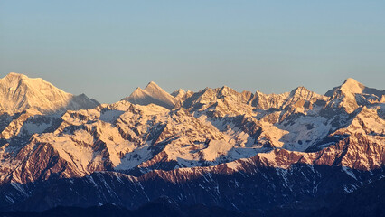 Majestic panoramic view of snow-capped Himalayan peaks bathed in the warm, golden light of either...