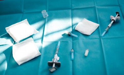 Syringes, gauze and medical equipment resting on sterile drape