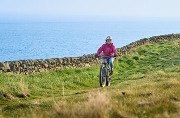 active senior woman riding her electric mountain bike at Mull of Galloway,  the southern most point...