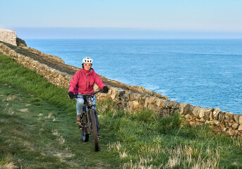 active senior woman riding her electric mountain bike at Mull of Galloway,  the southern most point...