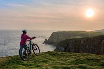 Fototapeta premium active senior woman riding her electric mountain bike at Mull of Galloway, the southern most point of Scotland, UK
