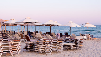 Empty sunbeds and umbrellas on beach at evening