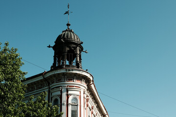 Historic red and white building with ornate tower and metal dome in Vrsac, Serbia, under clear blue sky.
