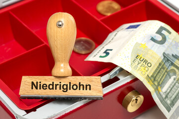 Ein Holzstempel ist beschriftet mit dem Aufdruck Niedriglohn