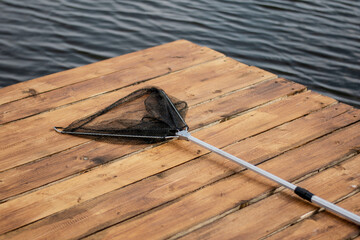 Fishing landing net for fish, fishing tackle on wooden pier