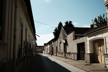Narrow old street with historic houses in Vrsac town, Serbia, under morning sunlight.