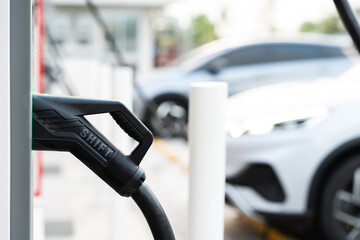 EV Charger Nozzle with "SHIFT" Text and Modern Electric Car Background