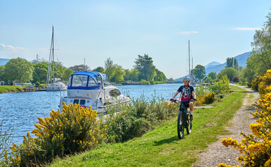 active senior woman riding her electric mountain bike along the Caledonian Canal near Fort William...