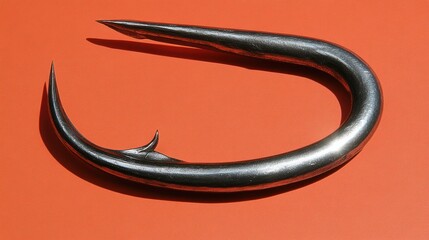 Close-up of a single, handcrafted, metallic, fishing hook with a sharp point, lying on an orange background.