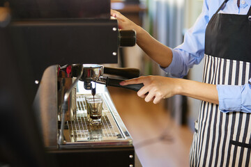 close up barista hands making fresh coffee from machine in the cafe