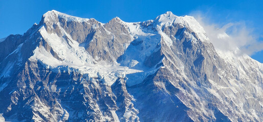 Majestic snow-capped peaks of the Chaukhamba massif in the Indian Himalayas, showcasing its rugged, icy terrain and the grandeur of the mountains under a clear blue sky.