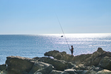 silhouette of a fisherman with a fishing rod against the sea