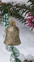 Gold glitter Christmas bell ornament, close-up. Winter holiday decoration. Snowy background