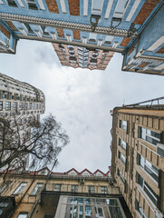 Upward view of buildings with cloudy sky. Urban architecture perspective showcasing modern and classic structures