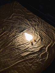 Illuminated lamp on textured fabric background, dim lighting. Soft shadow and warm glow