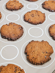 Baked chocolate chip cookies cooling on baking sheet lined with silicone mat