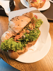 Croissant sandwich with fresh lettuce, vegetables, and toppings on wooden table