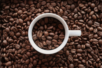 Espresso cup with coffee beans and background full of roasted coffee beans.