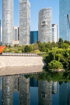 Reflection of Santa Fe's skyline on calm water near La Mexicana Park in Mexico City, showing harmony between architectural density and landscaped green public space