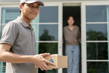 Happy smiling woman receives boxes parcel from courier in front house. Delivery man send deliver...