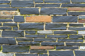 Various colored natural stones with mossy joints form a textured mosaic. The dark slabs are...