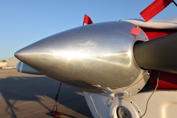 The shiny nose of a small parked airplane on the runway.