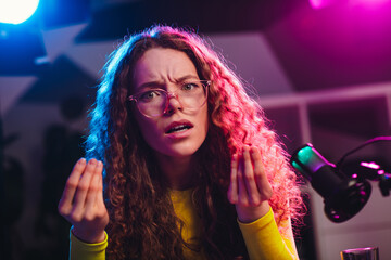 Young woman gesturing passionately in neon-lit room while broadcasting live social media content