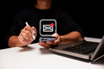A person using a smartphone and stylus, with a laptop nearby, and a digital notification icon...