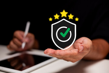 A person holds a digital shield icon with a green checkmark and five stars above it, symbolizing...