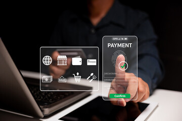 A person uses biometric fingerprint authentication on a transparent screen to confirm a secure online payment via laptop and tablet.