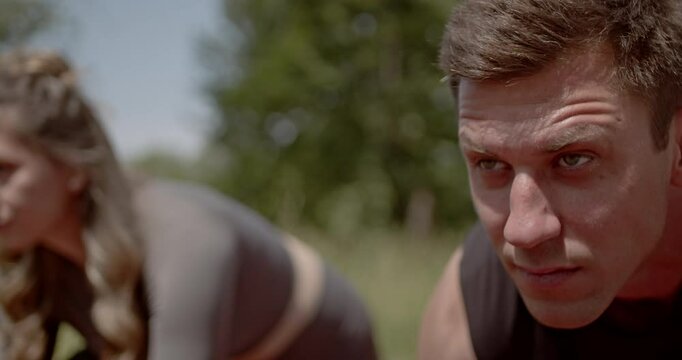 Fitness group doing bear crawls on a running track. Working out together outdoors during summer. - Powered by Adobe