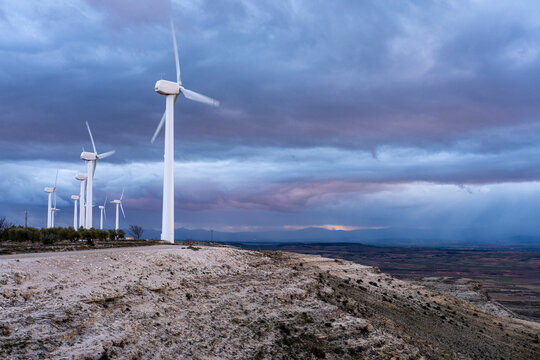 Multiple wind turbines on rocky terrain in Arag&oacute;n, Spain, under vibrant blue sky, representing durability and elevation in wind power infrastructure