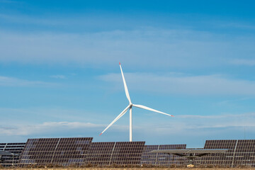 Single wind turbine rising above solar panels under clear skies in Aragón, Spain, showcasing clean energy infrastructure and sustainable power generation