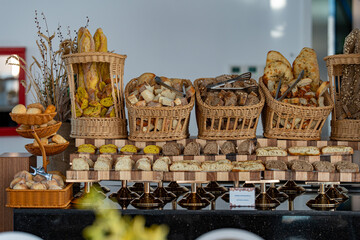 Creative display of various types of bread artfully arranged on a buffet table in a restaurant. A...