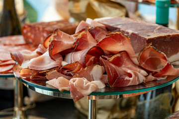 Photo of sliced red meat pieces with visible fat layers displayed on a buffet table. This rich and flavorful meat selection is perfect for charcuterie boards, catering events, or gourmet spreads