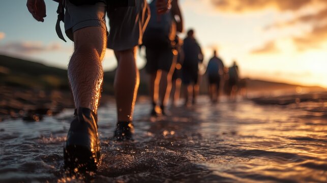 A group of hikers strolls along the beach, their feet splashing through the water as the sun sets, casting a warm glow on the horizon, creating a serene atmosphere.