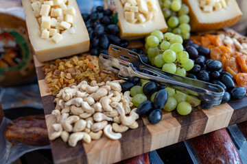 Photo of a snack platter featuring cashew nuts, cheese, and grapes. The elegant combination of textures and flavors offers a perfect balance of sweet, salty, and crunchy, ideal for wine pairing, charc