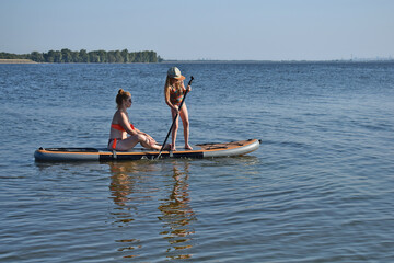 A girl and a woman are riding a SUP board.