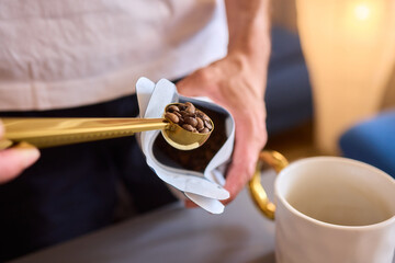 Pouring freshly ground coffee beans into a measuring cup for a perfect morning brew