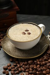 Aromatic coffee in cup, beans and grinder on black table, closeup