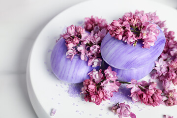 Soap bars, sea salt and lilac flowers on white table, closeup